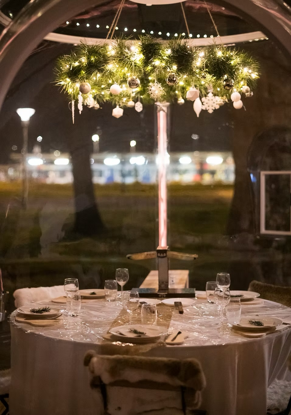 Table dressée à l'intérieur d'une bulle, sous une couronne de sapin illuminée
